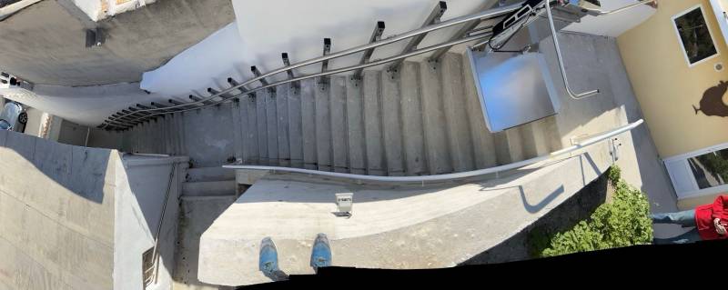 Vue d'ensemble de la plateforme oblique Lehner Stratos en extérieur dans un escalier droit avec palier intermédiaire à proximité de la mer à Marseille